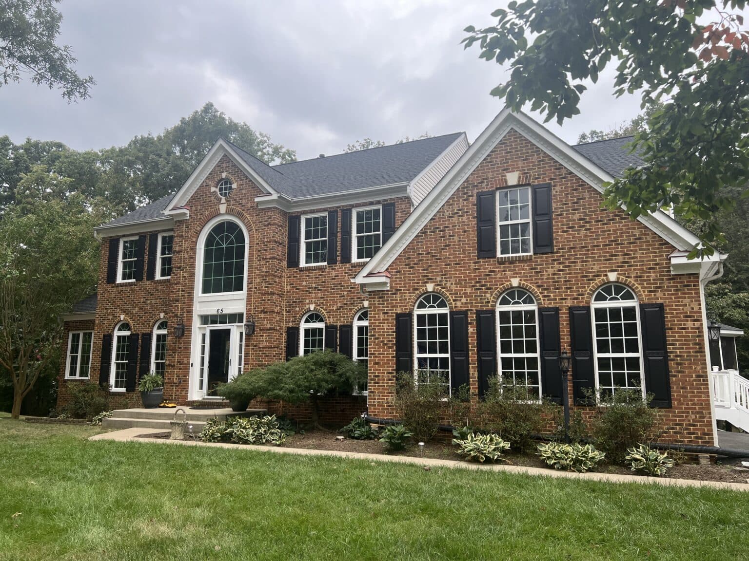 Two-story brick home with arched windows and landscaped front yard.
