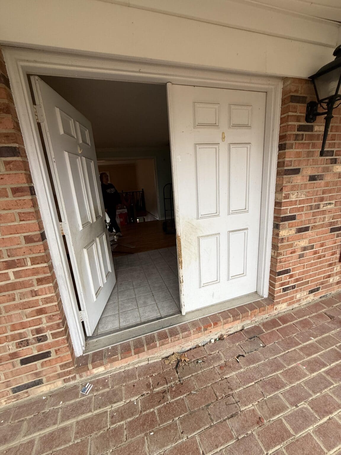 White paneled exterior door partially open, showing the home's interior before replacement.