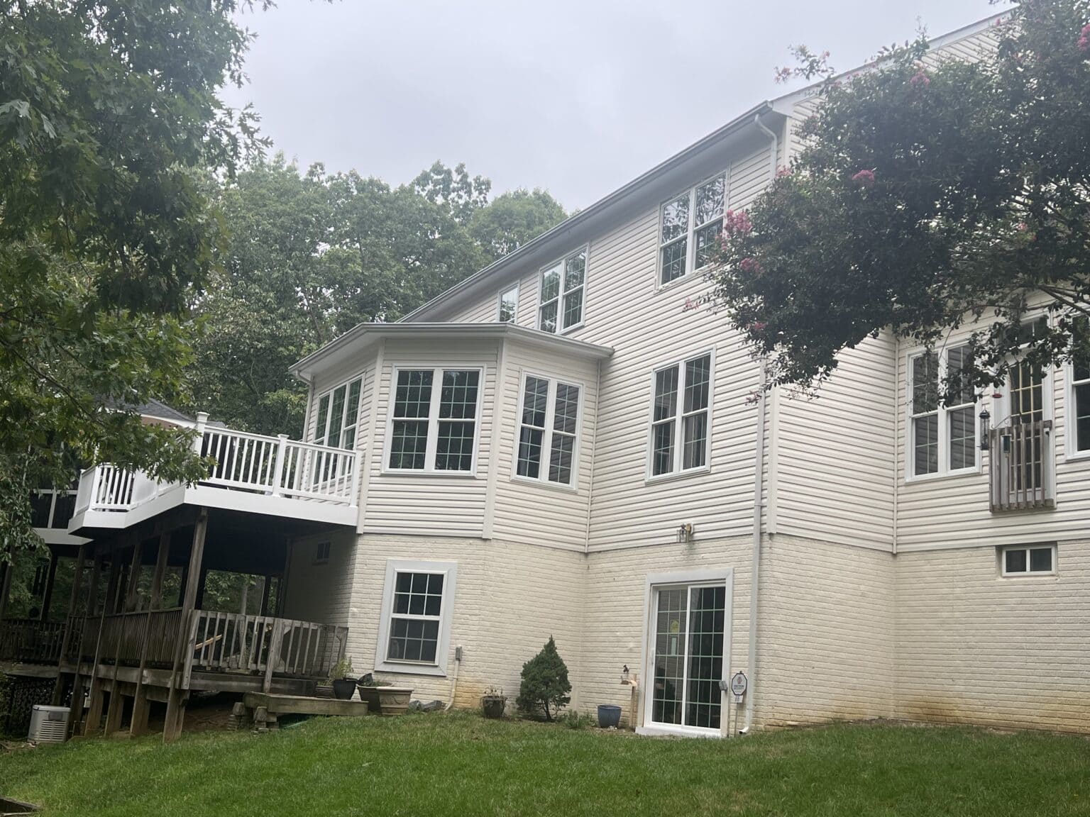Rear exterior of a white two-story home with multiple windows and a raised deck.