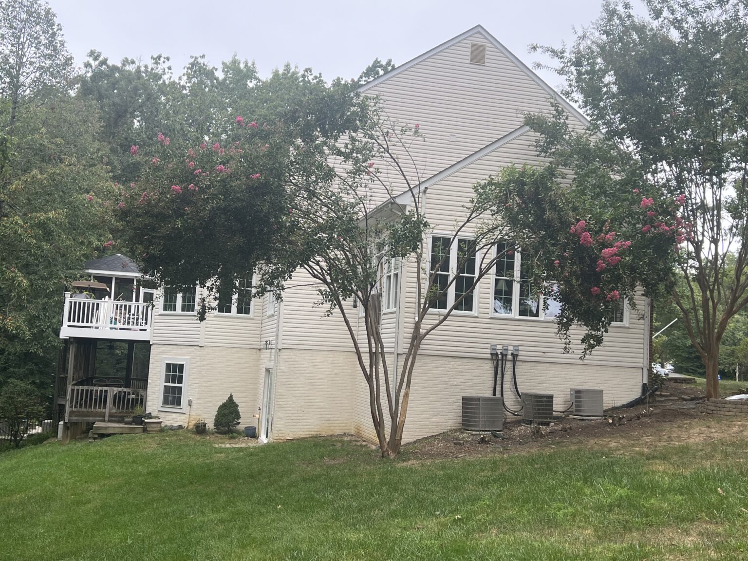 Side view of a white two-story home with several windows and surrounding trees.