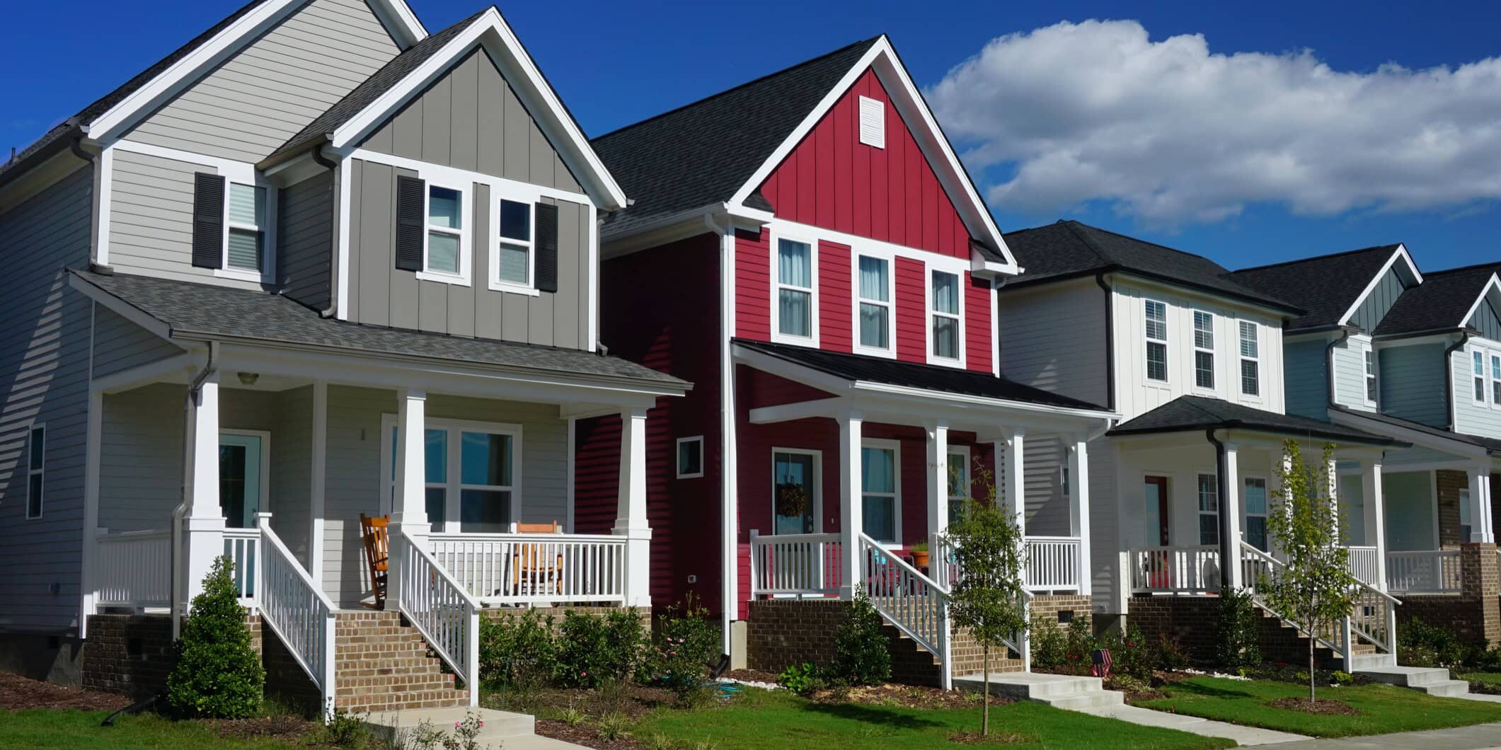 Row of two-story residential homes with white-framed windows and exterior doors showcasing window and door installation options.