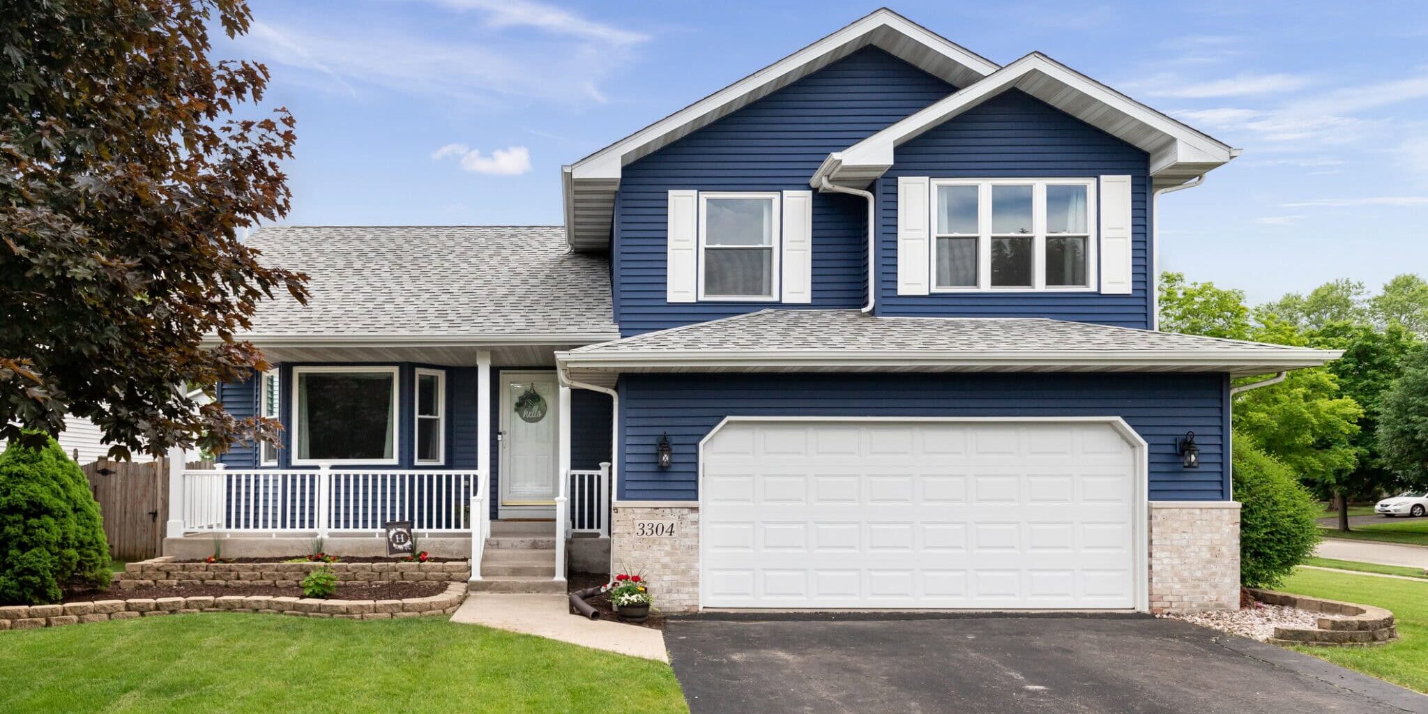Exterior of a suburban home with blue siding, a white front porch, and white shutters.